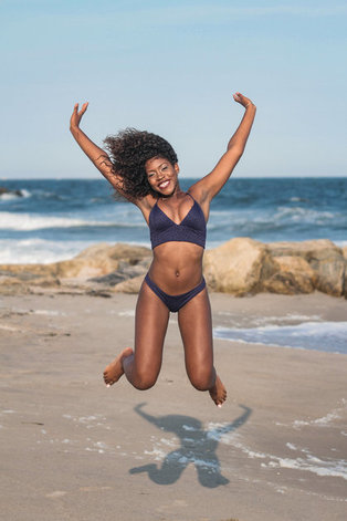 vrouw op strand in bikini springt