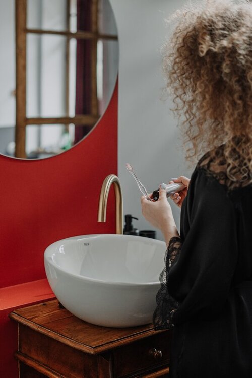 Vrouw voor spiegel poetst tanden. 